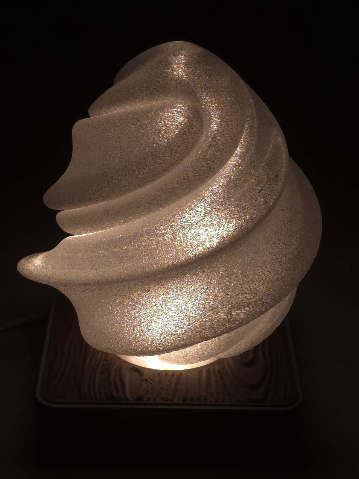 Lampa nocna z kloszem Lody włączona w ciemności — przezroczysty klosz na szarej podstawie