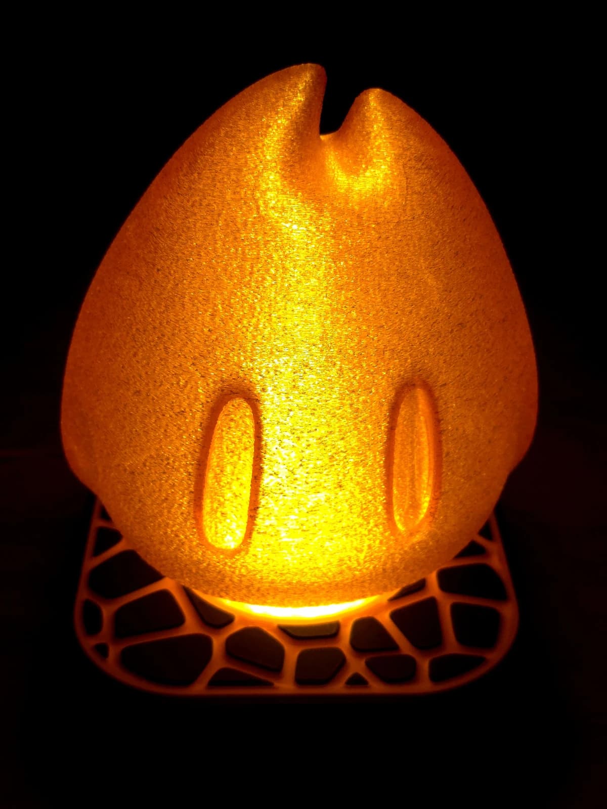 Lampa nocna z kloszem Flamy, włączona — pomarańczowy klosz świeci ciepłym światłem